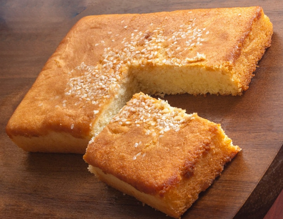 Maquesote cake on a wooden chopping board with an oblong piece cut off the main cake