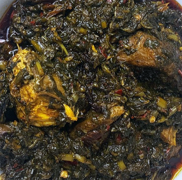 mboro mboro, senegalese stew of meat and sweet potato leaves in a red palm oil base served on a plate