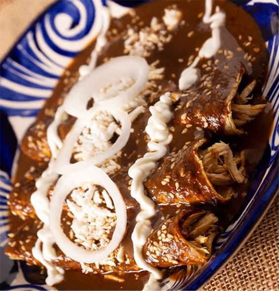 emnoladas on a plate topped with mole poblano, tofu and onion rings