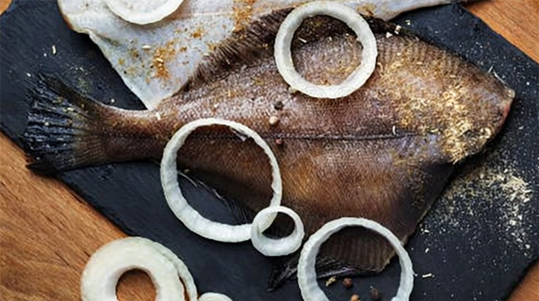 prepared plaice on a slate with onions ready for cooking