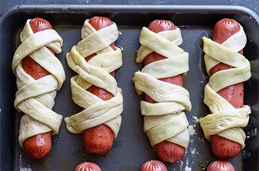 hot dogs wrapped in pizza dough on a baking tray