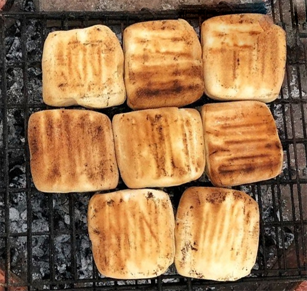 squares of Namibian braai bread cooking on a barbecue grill