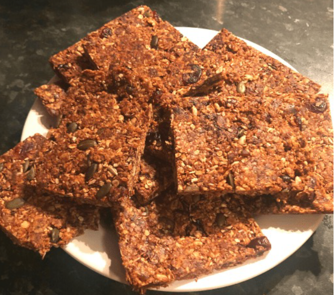 stack of no-bake peanut butter flapjacks with fruit and seeds piled on a plate
