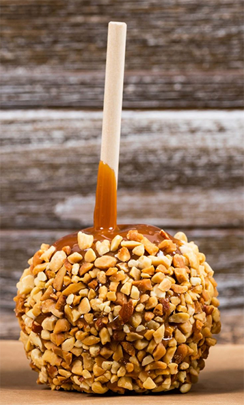 almond-coated toffee apple on a sheet of cardboard