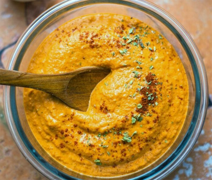 yellow bell pepper and oarweed sauce in a glass bowl with a wooden spoon