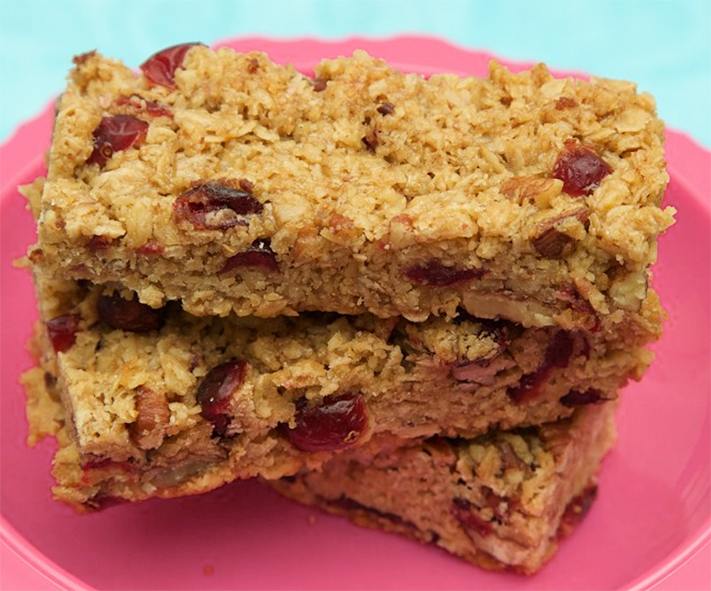 three oil-based cranberry and walnut flapjacks stacked on a plate