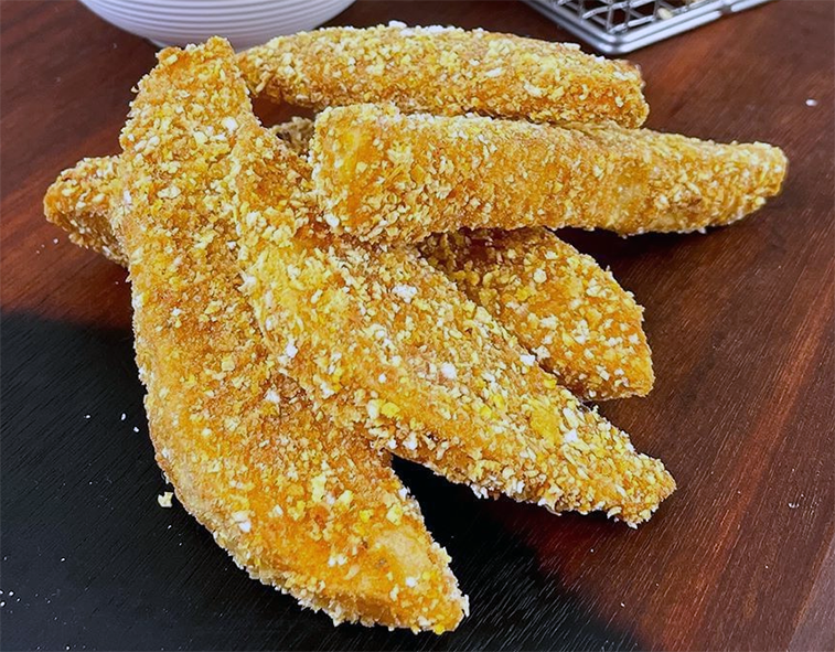 fish fillets coated in gari cassava meal before being fried arranged on a wooden table