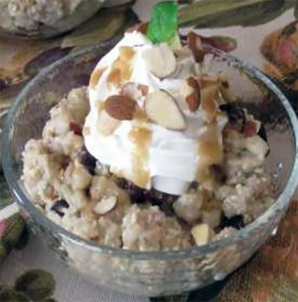 barley pudding in a glass bowl garnished with whipped cream
