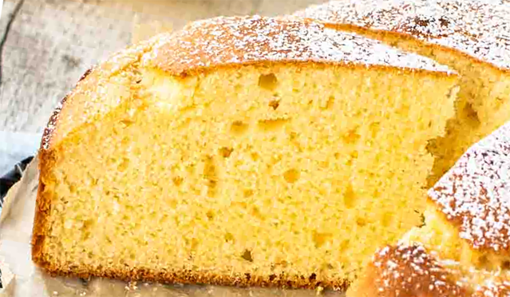 wedge of powdered sugar dusted lemon sponge cake on a wire rack