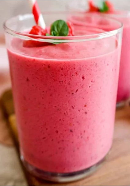 pink smoothie deluxe in a glass garnished with a sprig of mint