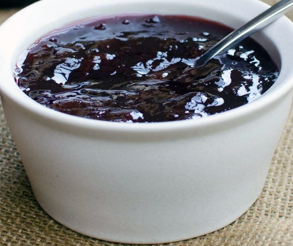 damson conserve in a white dish with a spoon