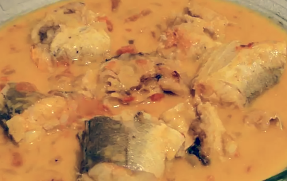 fish and taro in a coconut milk base with red oil and tomato puree in a glass casserole