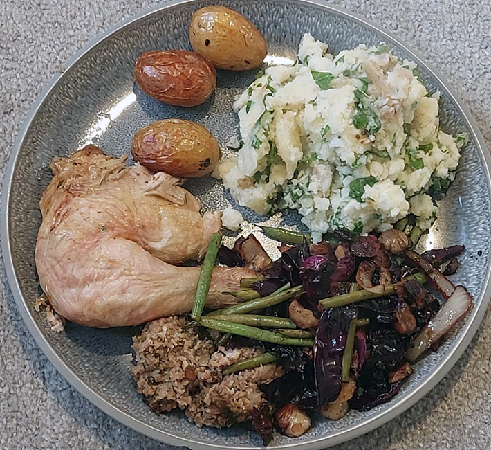 stuffing on a plate with vegetables, chicken leg, mash and roast potatoes