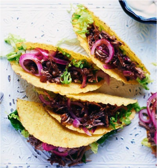 three pulled pork tacos on a white table-top