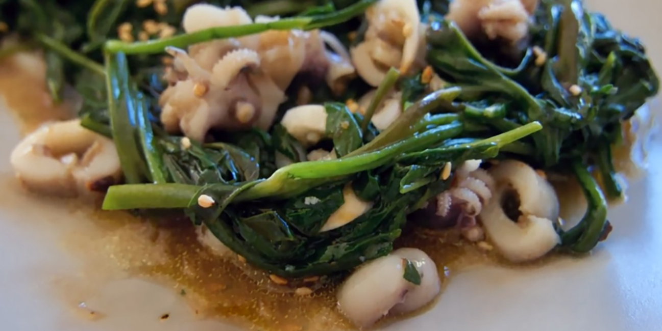 stir-fried dish of baby squid rings and water spinach in a soy sauce, sugar and lemon juice base served on a plate