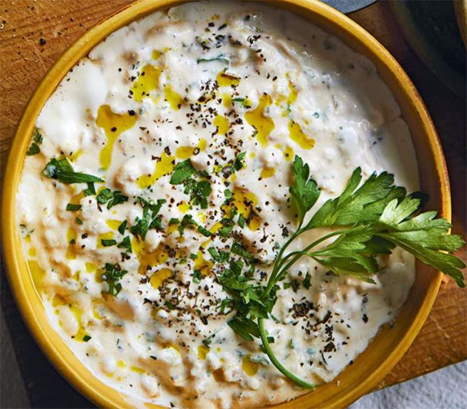 Armenian sapas, a yoghurt and barley soup served garnished with oil and a sprig of coiander leaves