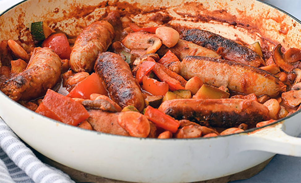 stew of sausages, butter beans and pumpkin with onion in a cocotte
