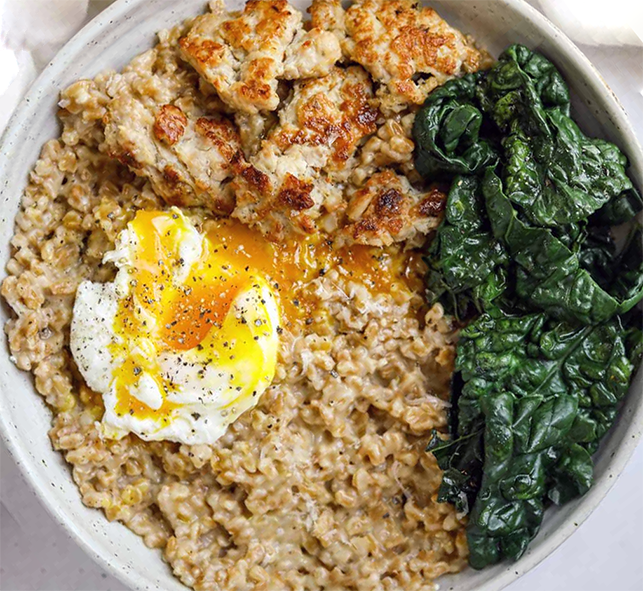 Farro porridge topped with sausage pieces, kale and a poached egg