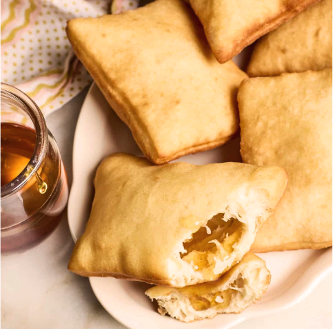 puffed fried sopapillas arranged near a jar of honey