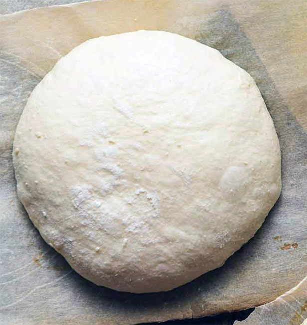 portion of sourdough pizza dough on a sheet of baking parchment