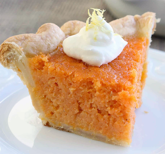 wedge of southern sweet potato pie garnished with a dollop of cream on a plate