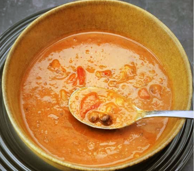 spicy carlin pea soup with roasted bell peppers in a soup bowl with a spoon