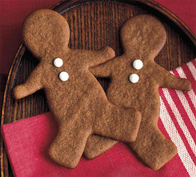 Two spicy Christmas gingerbread men with white candy buttons arranged on a wooden tray