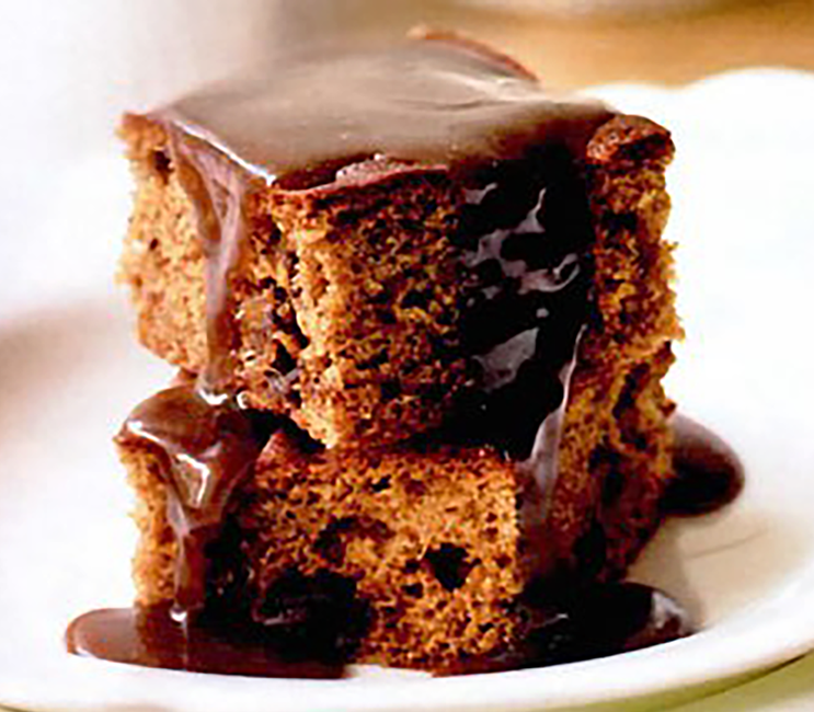two squares of sticky toffee pudding drizzled with toffee sauce