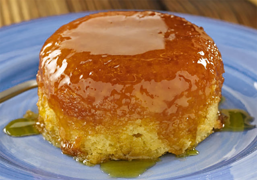 Sponge pudding with a syrup topping shown on a blue plate