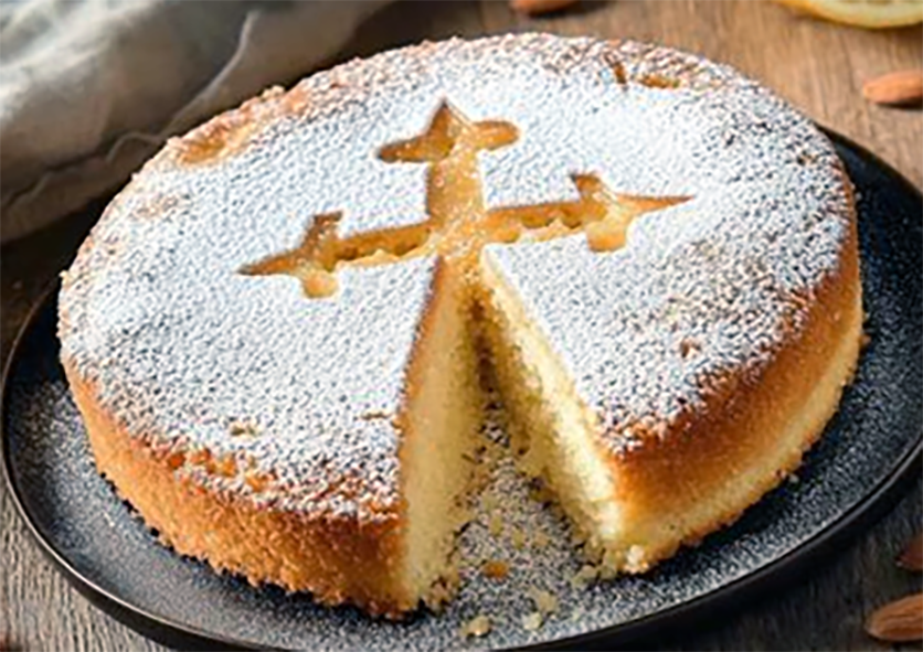 tarta de santiago on a plate with a wedge removed to reveal the inside