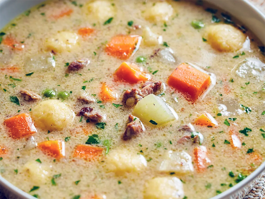 wild boar soup with vegetables and sour cream served in a soup bowl