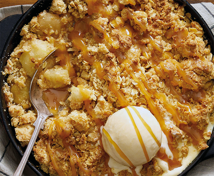toffee apple crumble topped with ice cream in a cast iron pan