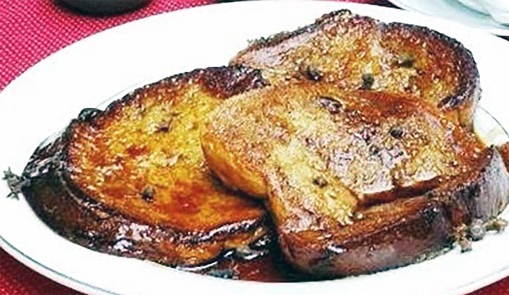 salvadorean torrejas smothered in syrup arranged in a serving dish
