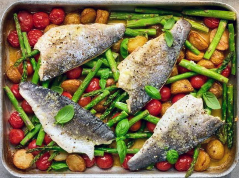 traybake of new potatoes, asparagus and cherry tomatoes topped with fillets of sea bass
