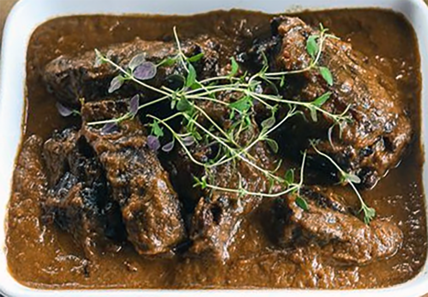 beef stewed in red wine in a white dish topped with thyme sprigs