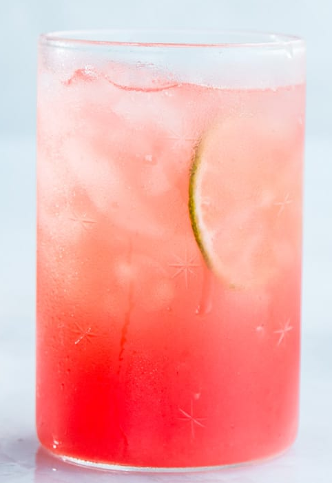 watermelon agua fresca in a glass over ice served with a slice of lime