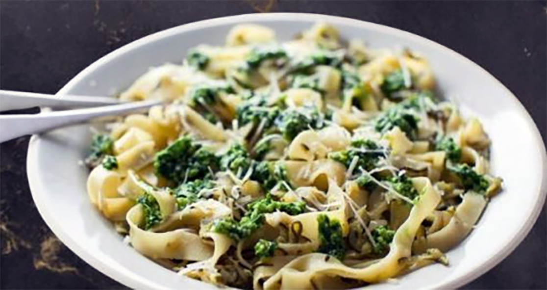 pasta primavera with wild greens and parmesan cheese in a milk sauce served on a plate
