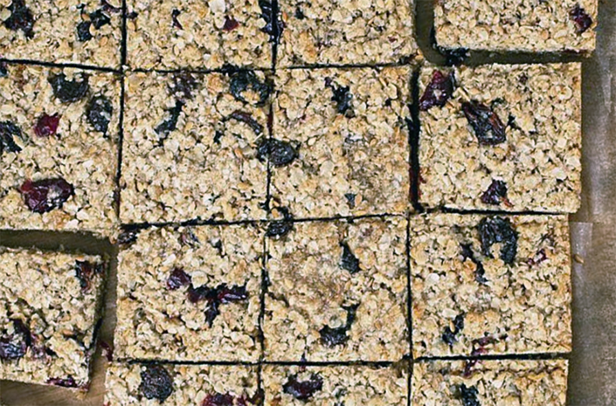 yoghurty oil-based raisin and poppy seed flapjacks cut into squares on a chopping board