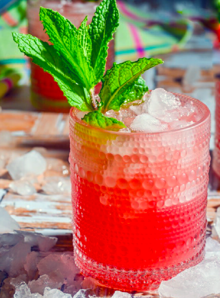watermelon agua fresca served over ice in a glass with a sprig of mint