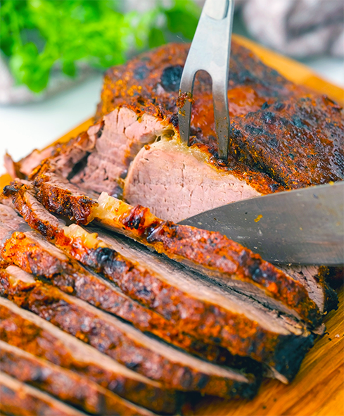 herb-crusted beef brisket cooked in an air fryer being sliced on a cutting board