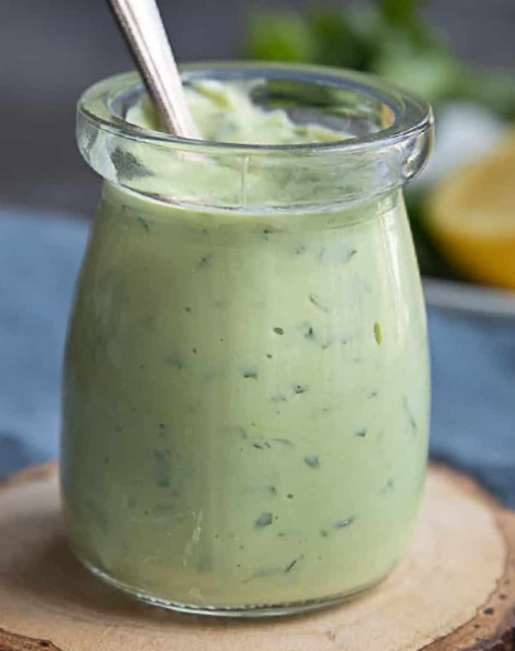 yoghurt-based salad dressing flavoured with avocado leaf in a jar with a spoon