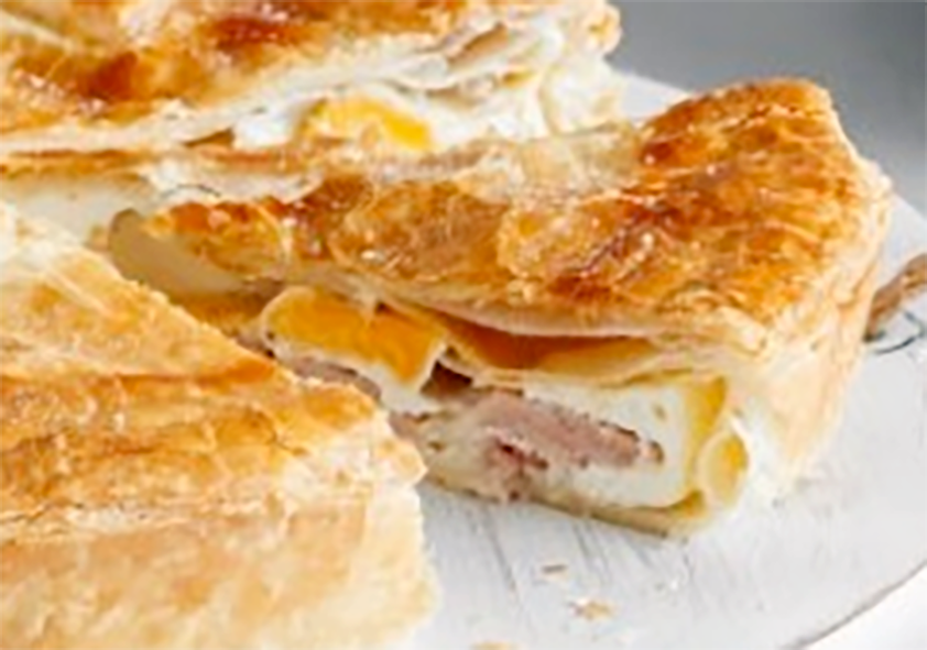 puff pastry bacon and egg pie, with a wedge removed from the main pie to reveal the filling