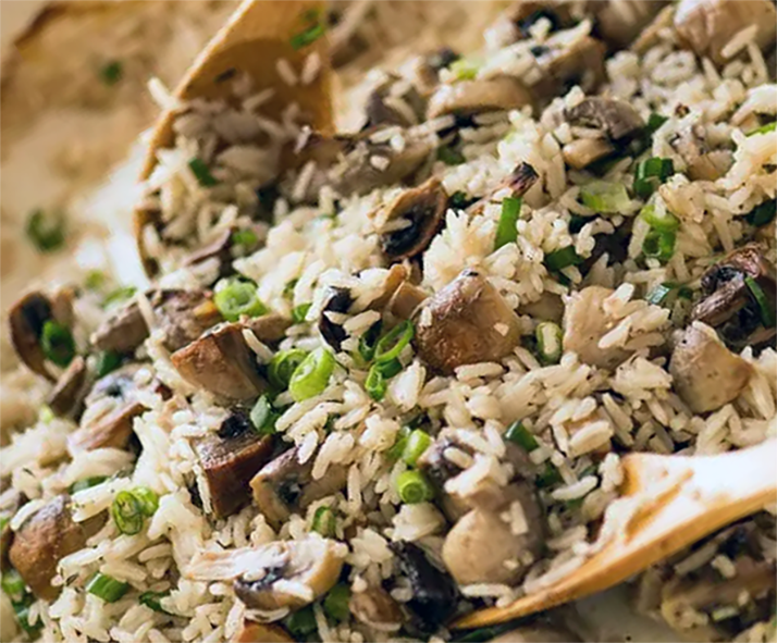 baked rice with mushrooms fluffed with a wooden spoon