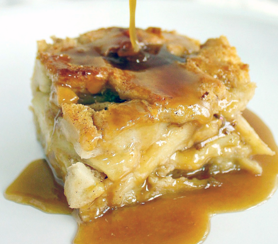 cajun bread pudding on a plate with hot rum sauce poured over