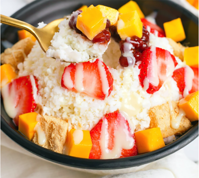 Bingsu, shaved ice, served in a bowl with a garnish of fresh fruit and condensed milk