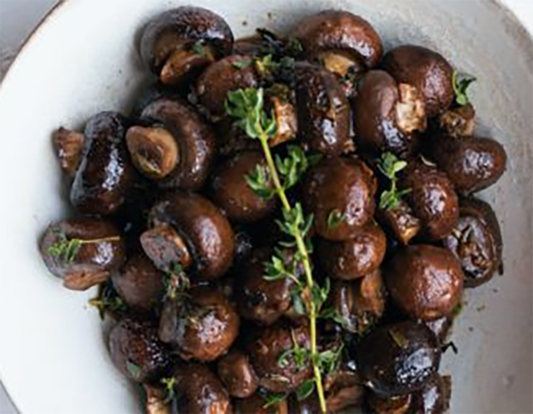 button mushrooms in balsamic vinegar in a bowl with a sprig of thyme