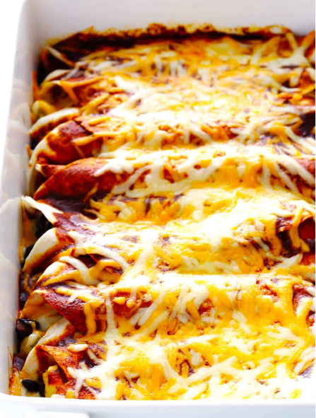 Chicken enchiladas with a grated cheese topping presented in a baking dish