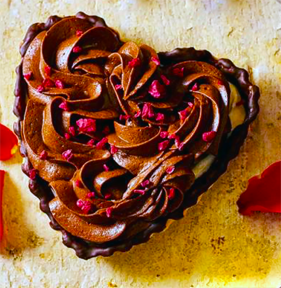 raspberry cream tart in the shape of a heart with a piped topping of chocolate mousse and a garnish of freeze-dried raspberry pieces