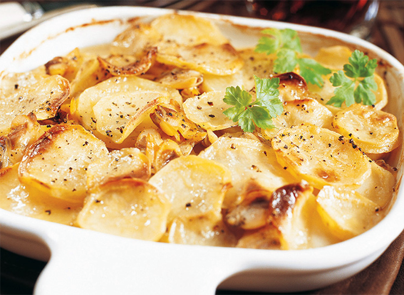clams and potatoes in a white ceramic dish baked in butter and clam cooking liquor