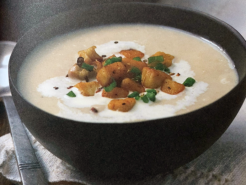 cream of giant puffball soup served in a bowl with a garnish of fried diced giant puffball pieces, chives and sour cream